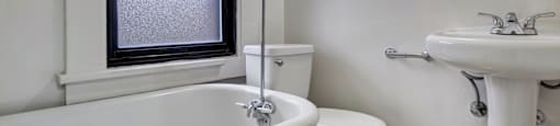 A white bathroom with a toilet, sink, and bathtub.
