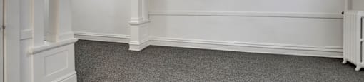 A room with white walls and a grey carpet.
