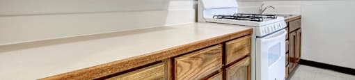 A kitchen with wooden cabinets and a white stove top oven.