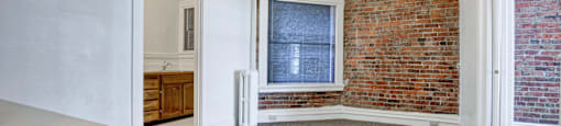 A room with a brick wall and a window.