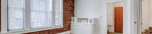 A room with a white cabinet and a window with blinds.