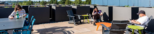 people sitting at tables and chairs on a roof terrace at Arbora Court, Washington, 98105