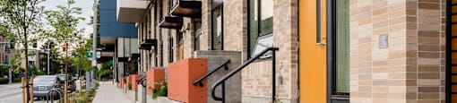 the facade of a building with orange doors and a sidewalk at Arbora Court, Washington