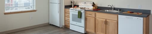 a kitchen with white appliances and wooden cabinets at The Aries at Bitter Lake Apartments, Washington