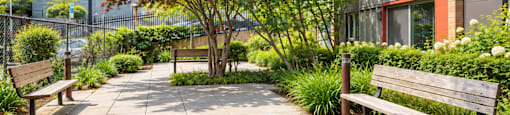 A park with benches and trees in front of a building.