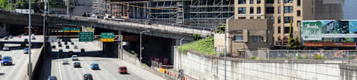 A city street with cars and a large building under construction.