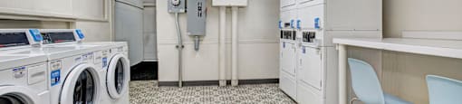 A laundry room with washers and dryers and a white cabinet.
