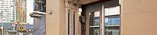 The front of a hotel with a glass door and steps leading up to it.