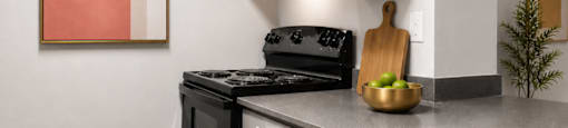 A kitchen with a black oven and grey cabinets.