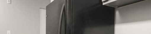 A black refrigerator stands next to a sink in a kitchen.
