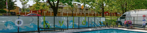 A pool surrounded by trees and a fence with graffiti on it.