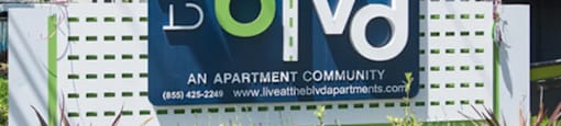 A sign for The Blvd apartment community with a phone number and website.