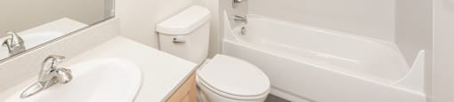A white bathroom with a toilet, sink, and bathtub.
