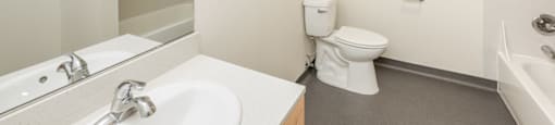 A white bathroom with a toilet, sink, and bathtub.