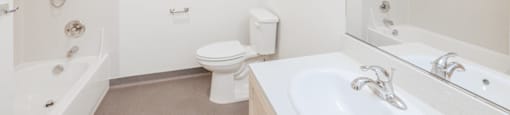 A white bathroom with a toilet, sink, and bathtub.