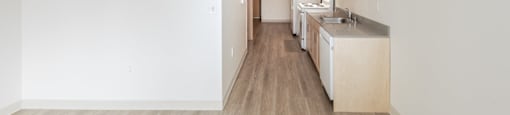 A kitchen with white walls and wooden floors.