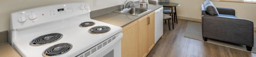 A kitchen with a stove top oven and a couch.
