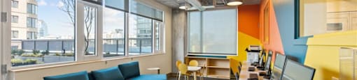 A modern office with a long white table and multiple monitors.
