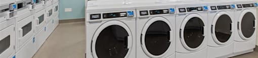 A row of white front load washing machines in a laundry room.