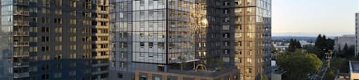 A modern glass building stands tall among other buildings.