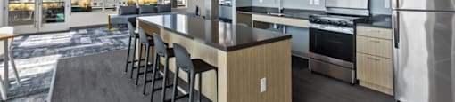 A modern kitchen with a long island and stainless steel appliances.