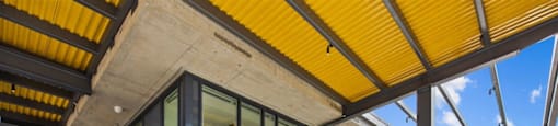 A rooftop patio with a yellow awning and several chairs.