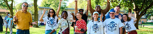 A group of people wearing white t-shirts with the text "CBC" are standing in a park.