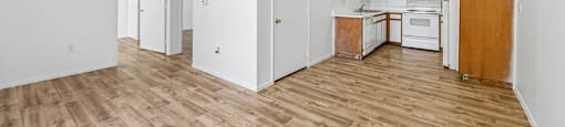 A kitchen with white walls and wooden floors.