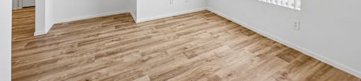 A room with wooden flooring and white walls.