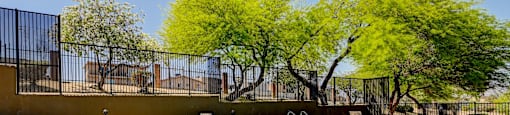 a swimming pool with a fence around it and trees in the background at Maryland Villas Apartments, Las Vegas