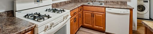 A kitchen with white appliances and wooden cabinets.