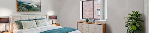 A bedroom with a large bed, a ceiling fan, and a painting on the wall at Birnam Wood Apartments, Monroeville, PA