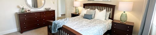 A bedroom with a bed, dresser, and mirror.