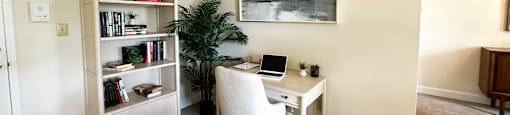 A room with a desk, chair, and bookshelf.