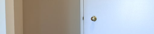 A white door with a gold handle is in a room with a wood floor.