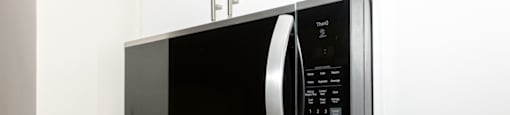 A silver microwave oven with a digital display and control panel.