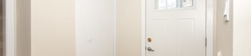 A white door with a window above it in a room.
