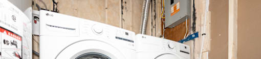 Two white front load washing machines in a laundry room.