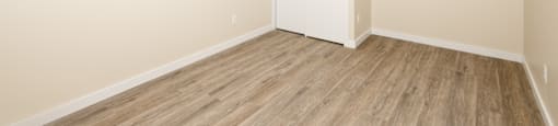 A room with a white door and wooden flooring.