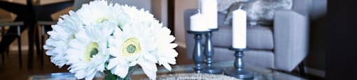 A vase of white flowers sits on a glass table.