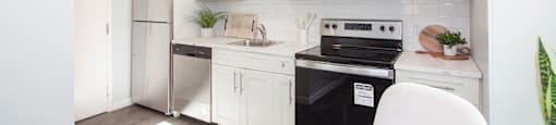 a kitchen with white cabinets and a black stove top oven for rent in Wpg