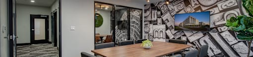 a meeting room with a large table and chairs and a mural on the wall