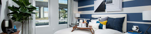 a bedroom with a large bed with white and blue bedding and a blue and white striped