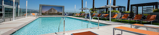 a large swimming pool with lounge chairs and umbrellas on a sunny day