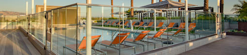 a pool with orange lounge chairs and palm trees in the background