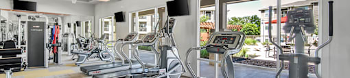 a gym with treadmills and other exercise equipment and windows