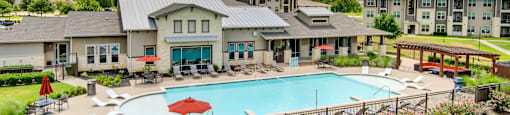 a swimming pool with lounge chairs and umbrellas in front of a building
