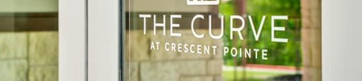 the cure at crescent pointe logo on glass door