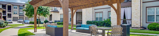a patio with a table and chairs under a wooden pavilion