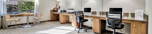 two desks with computers and chairs in a room with a window